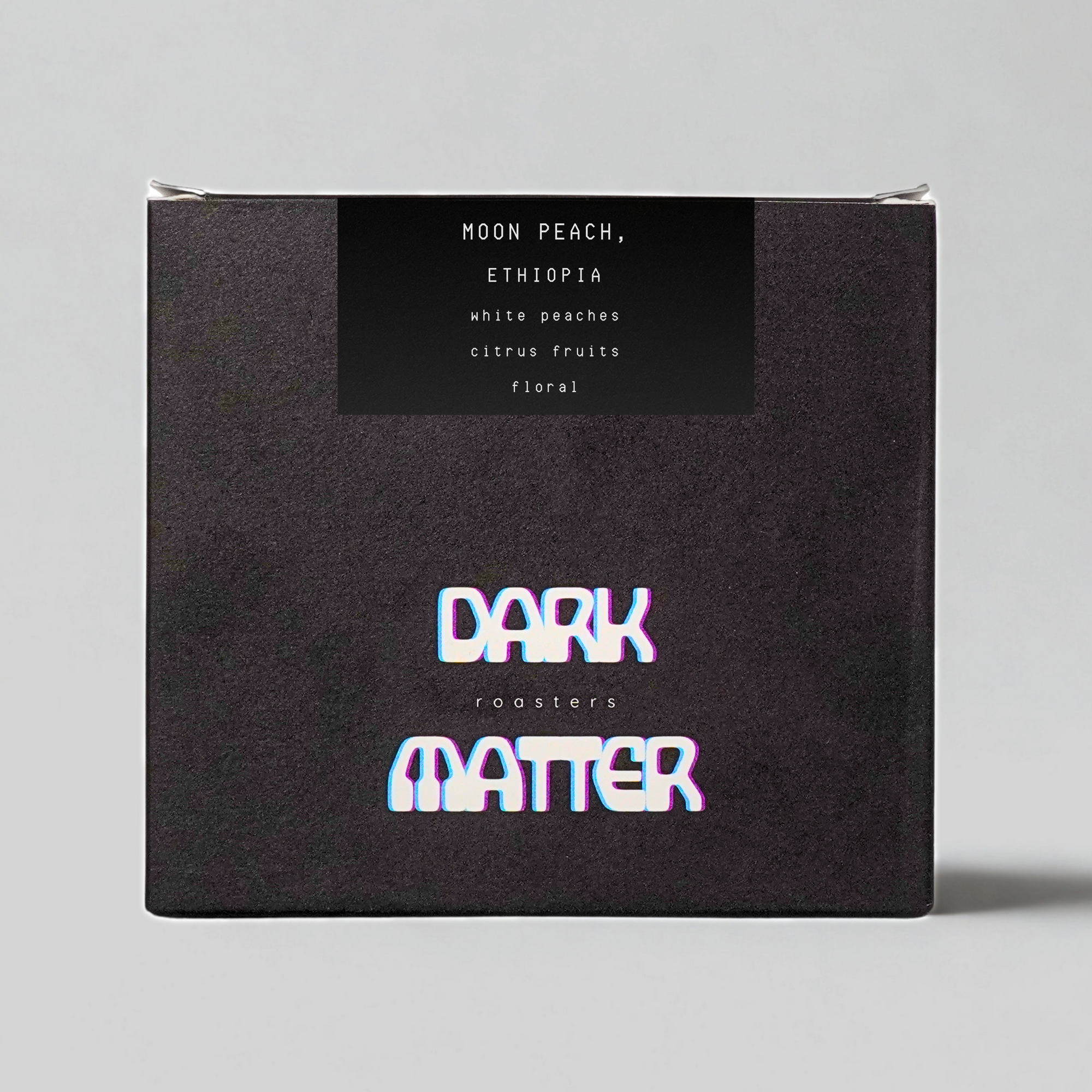 Dark Matter moon peach coffee packaging with branding on a gray background